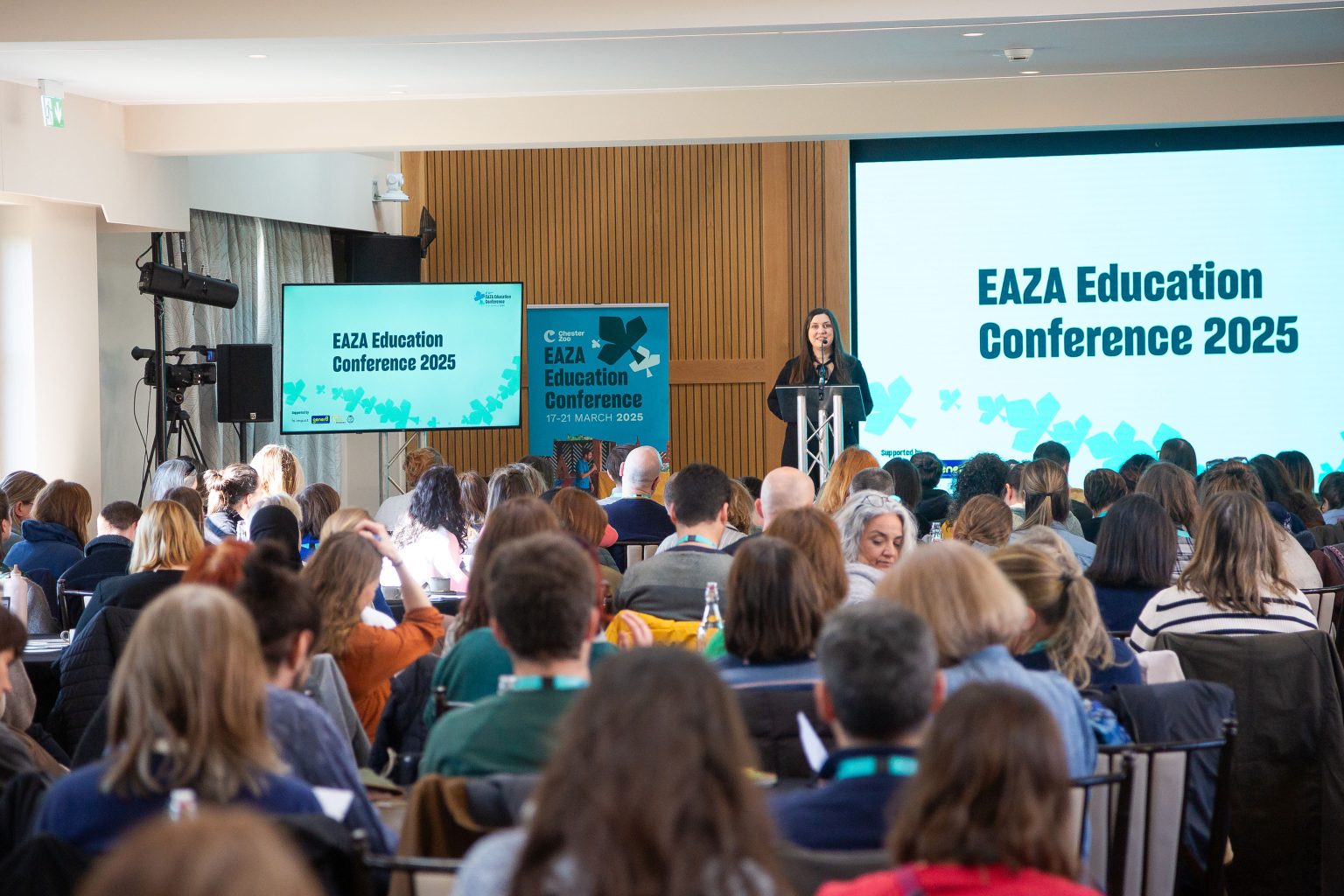 A group of people sit in an auditorium listening to a speaker during the European Association of Zoos and Aquaria (EAZA) Education Conference, hosted by #NatureForAll partner Chester Zoo in March 2025.